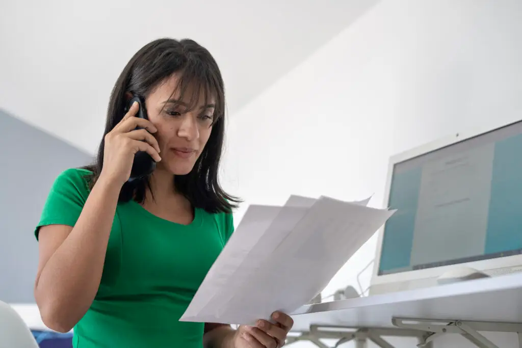 A mom on the phone in a green shirt calling to get her child's medical record corrected